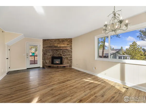 a view of an empty room with a fireplace a chandelier and wooden floor