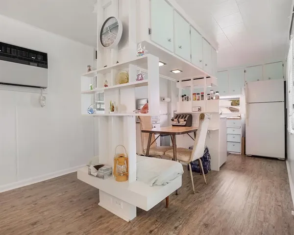 a room with a wooden floor and white cabinets