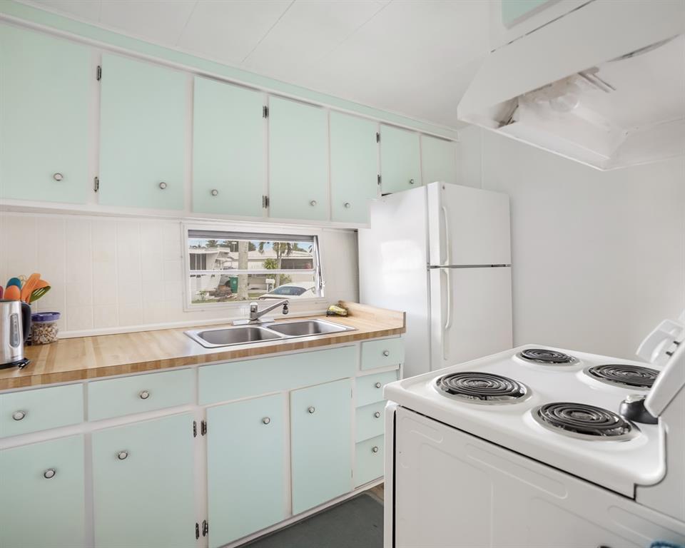 Park City Davie, FL 33324 - Photo 15 of 26 a kitchen with a sink a stove a refrigerator and white cabinets