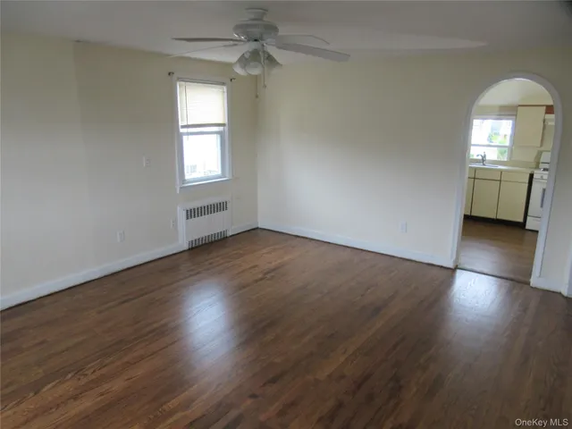 an empty room with wooden floor cabinet and windows