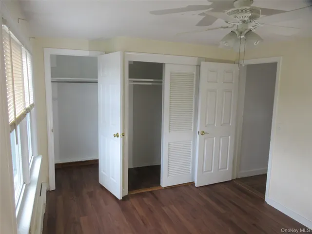 an empty room with wooden floor cabinet and windows