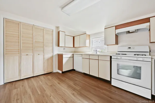 a white kitchen with a sink cabinets stainless steel appliances and wooden floor