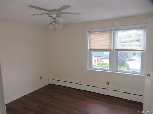 an empty room with wooden floor windows and fan