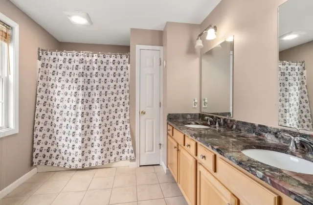 a bathroom with a granite countertop double vanity sink and a mirror
