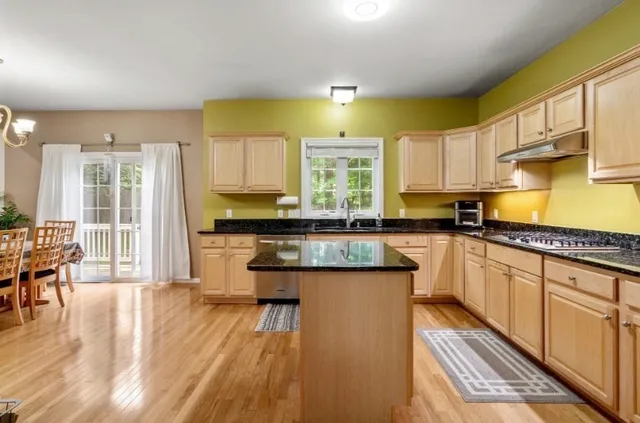 a kitchen with stainless steel appliances granite countertop a stove a sink dishwasher and a microwave oven with wooden floor