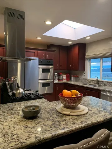 a kitchen with stainless steel appliances granite countertop a sink a stove and a wooden cabinets