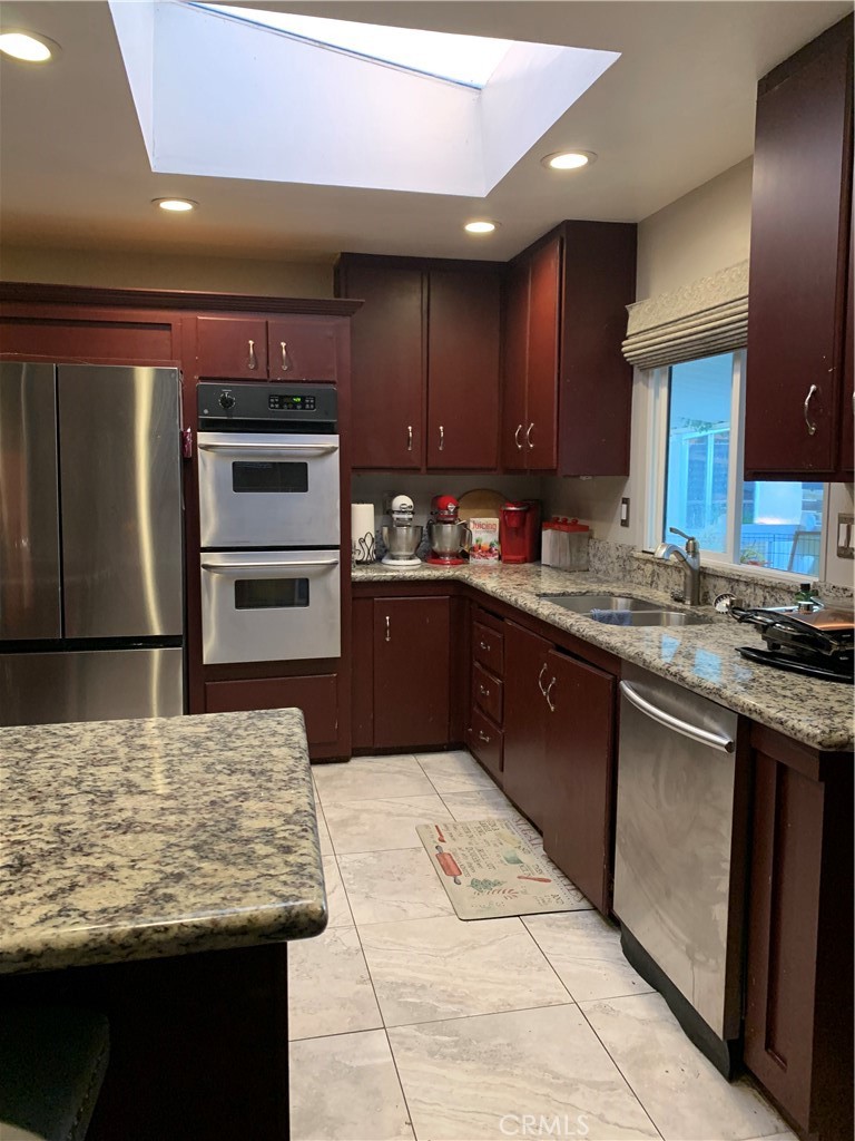 19009 South Laurel Park Road, Unit 248 Rancho Dominguez, CA 90220 - Photo 13 of 20 a kitchen with kitchen island granite countertop wooden cabinets a sink and stainless steel appliances