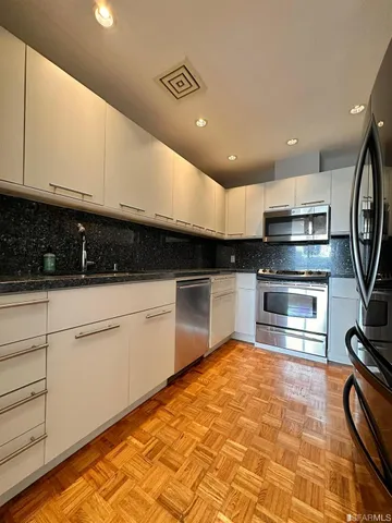 a kitchen with kitchen island granite countertop a sink cabinets and stainless steel appliances