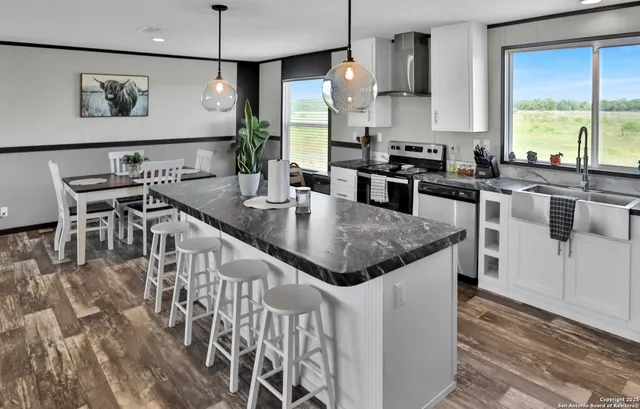 a kitchen with stainless steel appliances granite countertop a stove a refrigerator a kitchen island with a dining table and chairs