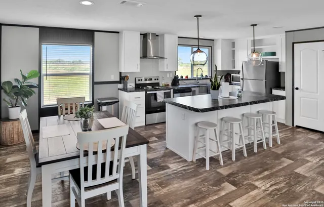 a kitchen with stainless steel appliances kitchen island granite countertop a kitchen island a stove a table and chairs