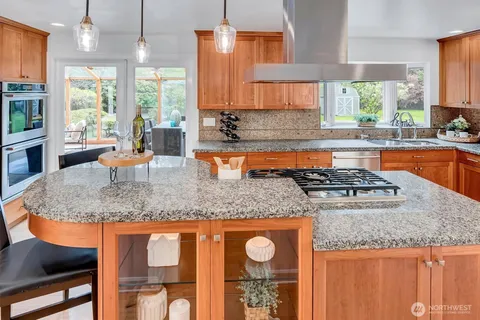 a kitchen with stainless steel appliances granite countertop a sink a stove and a wooden cabinets