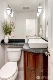 a bathroom with a granite countertop toilet sink and mirror