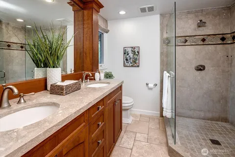 a bathroom with a granite countertop sink a toilet a mirror and shower