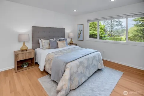 a bedroom with a bed lamp on table and a large window