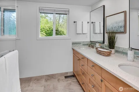 a bathroom with double vanity sink a mirror and a shower