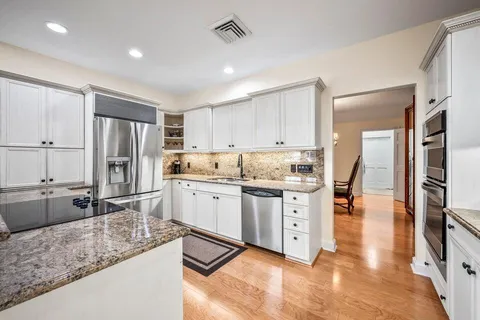 a kitchen with stainless steel appliances granite countertop a sink refrigerator and cabinets