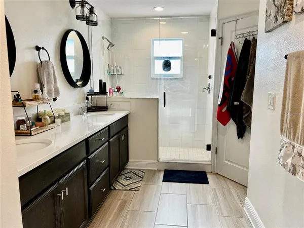 a bathroom with a double vanity sink a toilet a mirror and shower