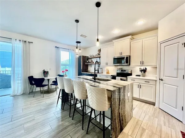a large kitchen with white cabinets stainless steel appliances a dining table and a wooden floor
