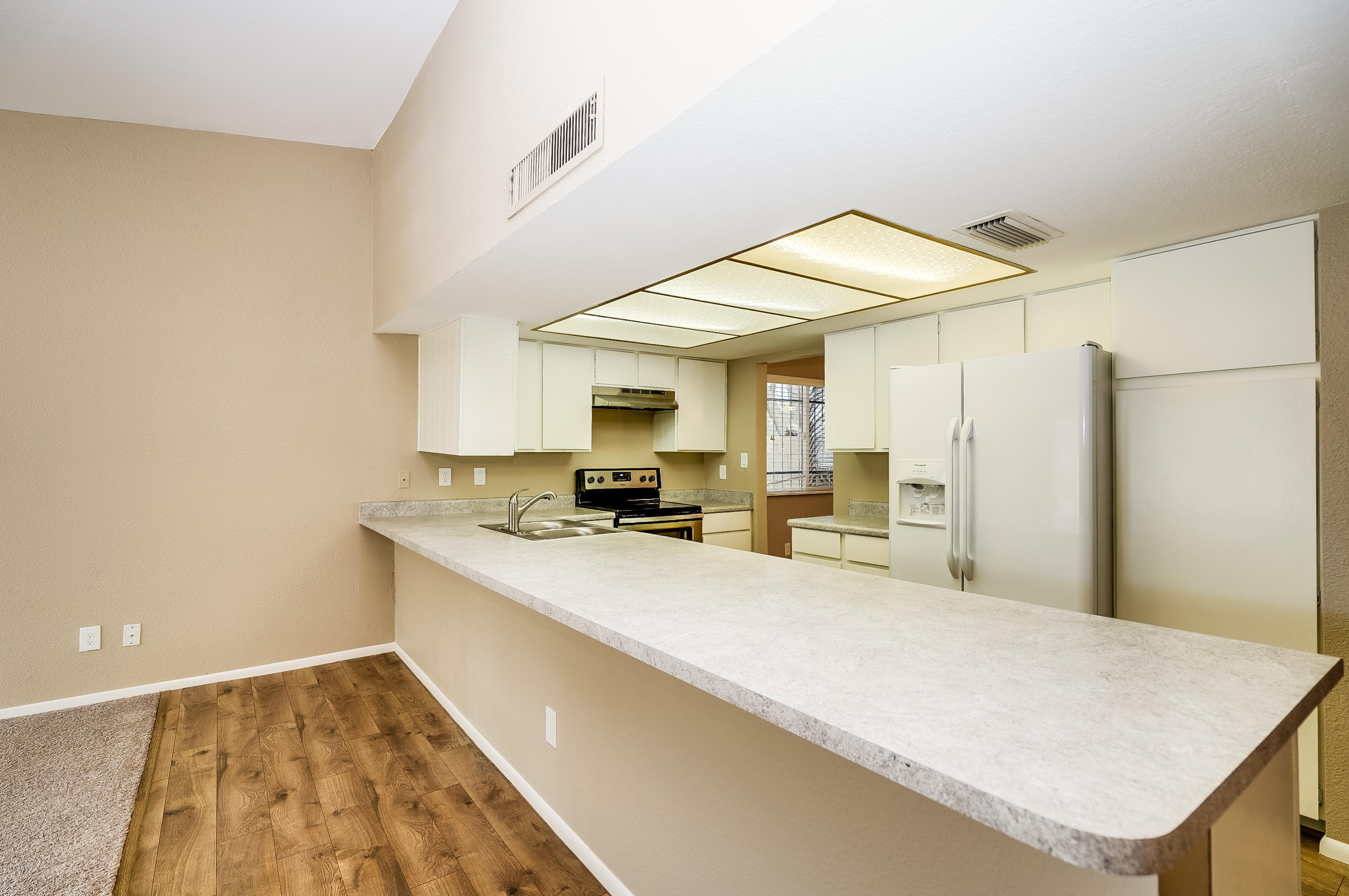 6509 West Camelback Road Phoenix, AZ 85033 - Photo 9 of 25 a large white kitchen with a sink and a refrigerator