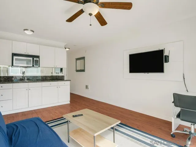 a living room with a flat screen tv and kitchen view