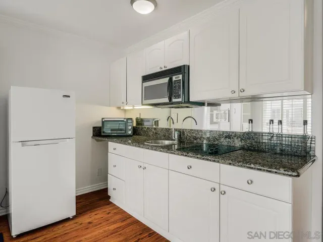 a kitchen with granite countertop white cabinets and white appliances