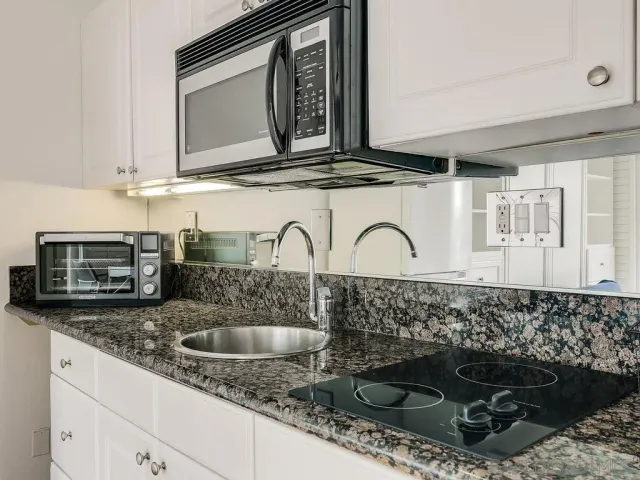 a kitchen with granite countertop a sink stainless steel appliances and cabinets