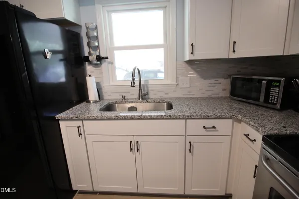 a kitchen with granite countertop white cabinets and black appliances