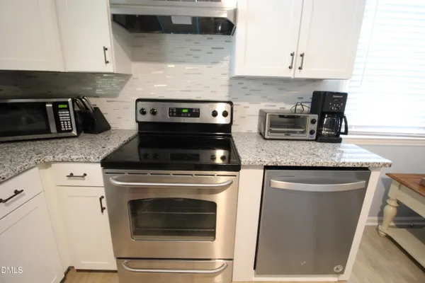 a kitchen with granite countertop cabinets stainless steel appliances and wooden floor