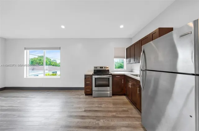 a kitchen with a refrigerator a stove top oven and a wooden floor