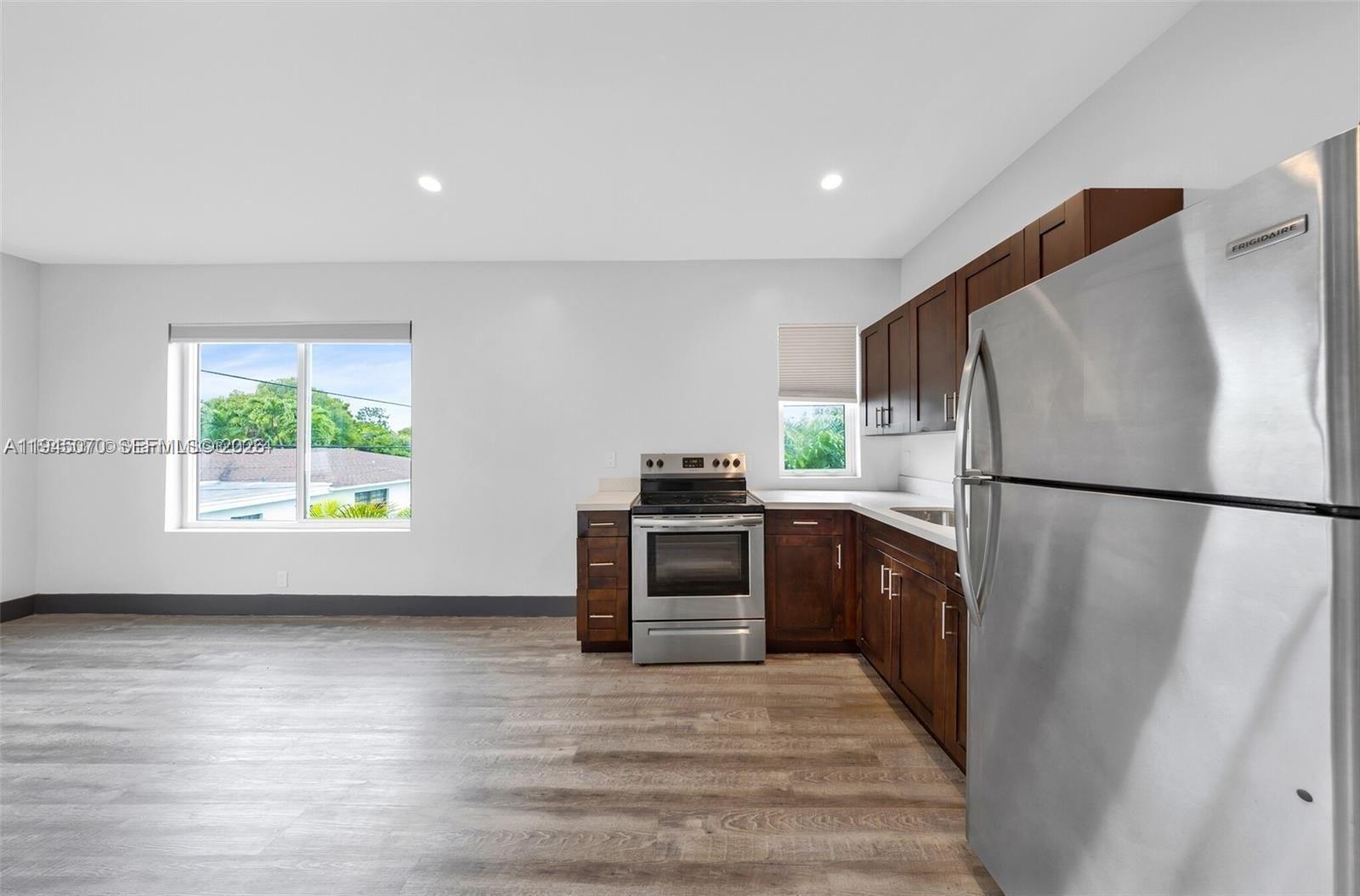 1020 Southwest 23rd Avenue, Unit 3 Miami, FL 33135 - Photo 7 of 15 a kitchen with a refrigerator a stove top oven and a wooden floor