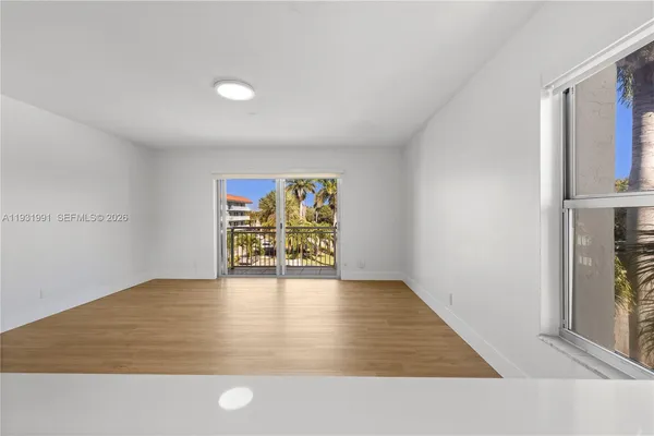 an empty room with wooden floor and windows