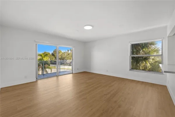 a view of an empty room with window and wooden floor
