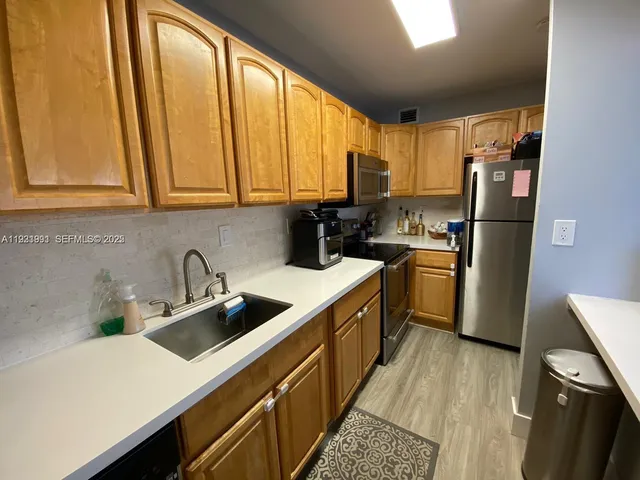 a kitchen with a sink a refrigerator a window and cabinets
