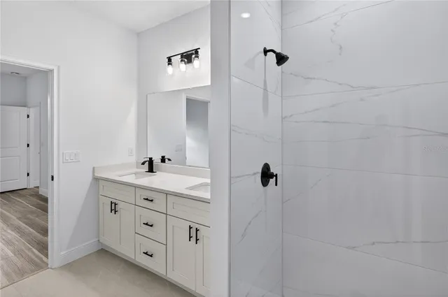 a bathroom with a double vanity sink a toilet a mirror and shower