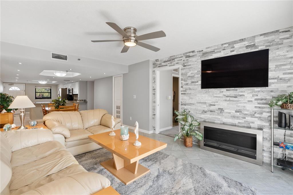 14001 Gulf Boulevard, Unit 201 Madeira Beach, FL 33708 - Photo 13 of 36 a living room with furniture a fireplace and a flat screen tv