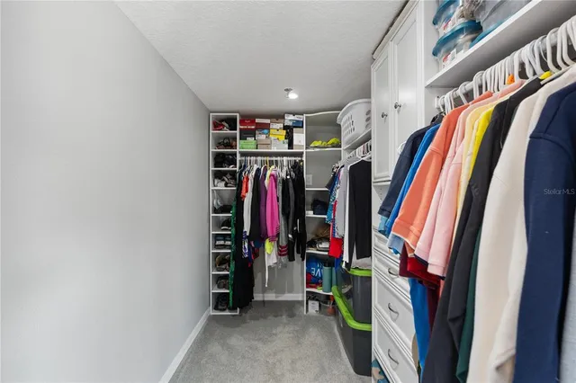 a view of walk in closet with clothes and shoes