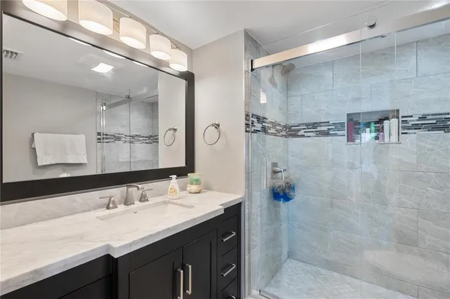 a bathroom with a granite countertop sink a mirror and shower