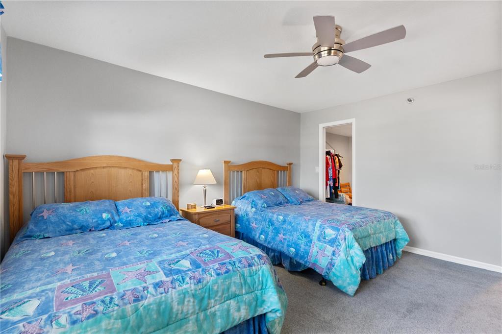 14001 Gulf Boulevard, Unit 201 Madeira Beach, FL 33708 - Photo 23 of 36 a bedroom with two beds and ceiling fan