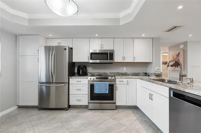 a kitchen with stainless steel appliances granite countertop a refrigerator a stove a sink and a microwave