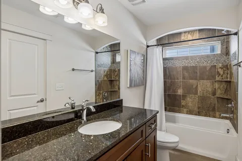 a bathroom with a granite countertop sink a toilet and bathtub