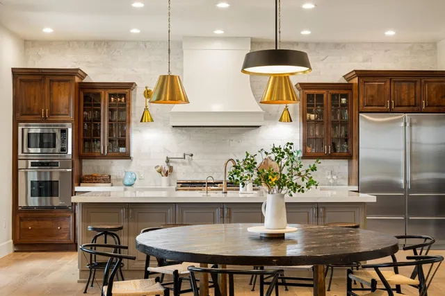 a kitchen with stainless steel appliances granite countertop a dining table and chairs