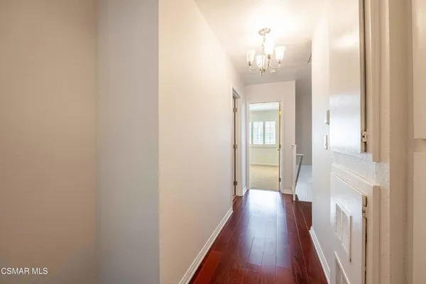 a view of a hallway with wooden floor and a chandelier
