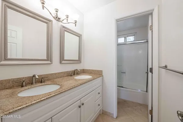 a bathroom with a granite countertop double vanity sink and mirror