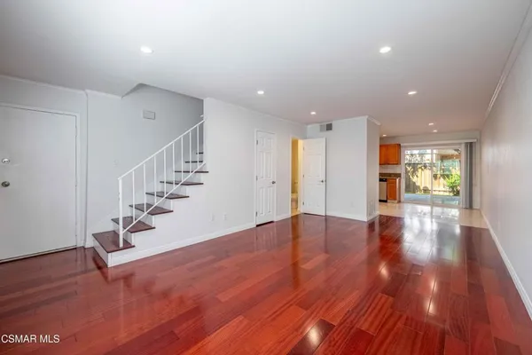 a view of an empty room with wooden floor and stairs