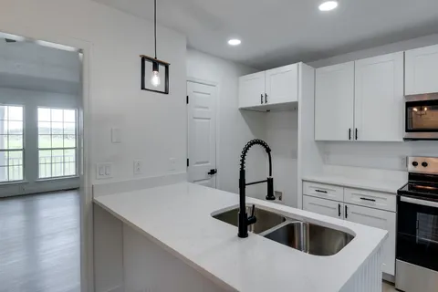 a kitchen with a sink a stove a refrigerator and cabinets