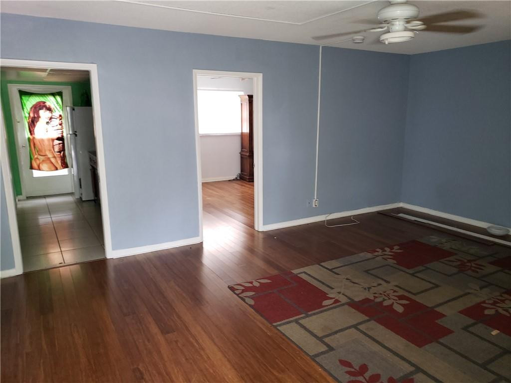 3212 Colony Club Road, Unit 2 Pompano Beach, FL 33062 - Photo 4 of 9 an empty room with wooden floor staircase and windows