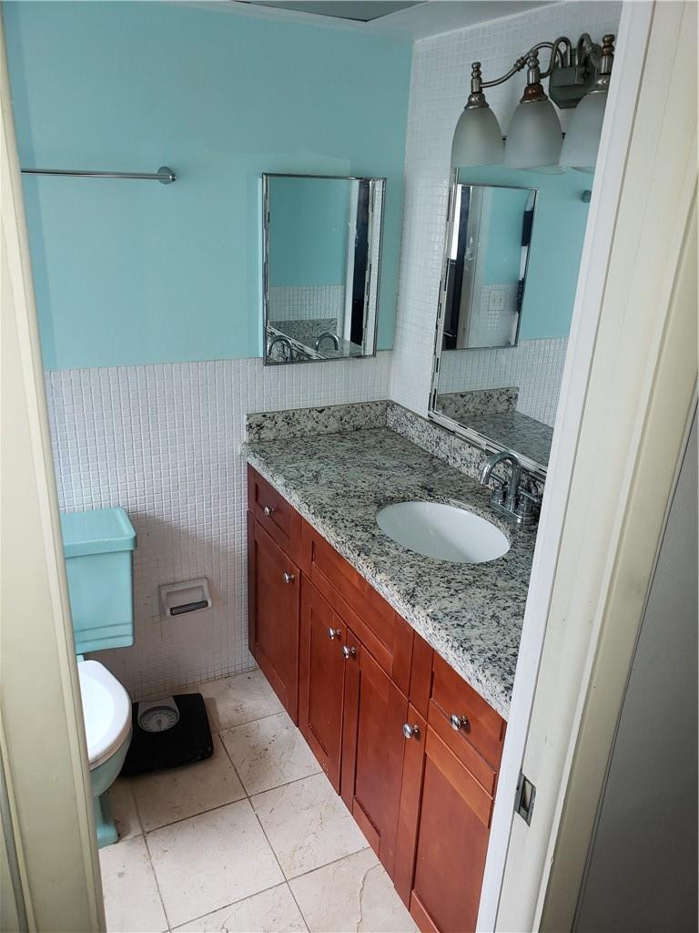 3212 Colony Club Road, Unit 2 Pompano Beach, FL 33062 - Photo 8 of 9 a bathroom with a granite countertop sink and a mirror
