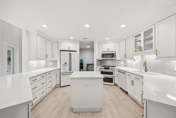 a large kitchen with white cabinets stainless steel appliances and a window