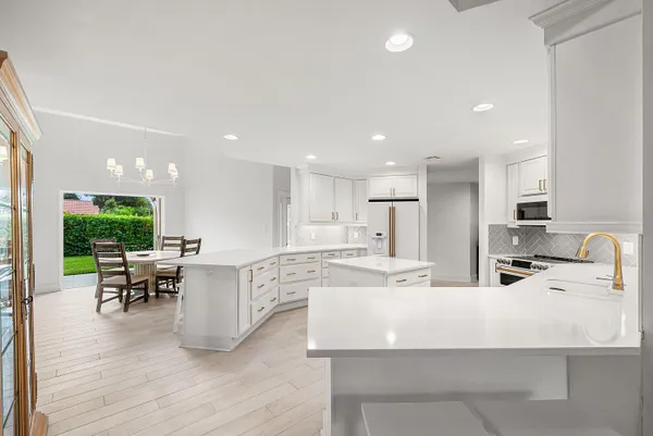 a large kitchen with kitchen island a dining table chairs and white cabinets