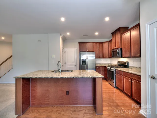 a large kitchen with stainless steel appliances kitchen island granite countertop a stove a sink a refrigerator and a microwave